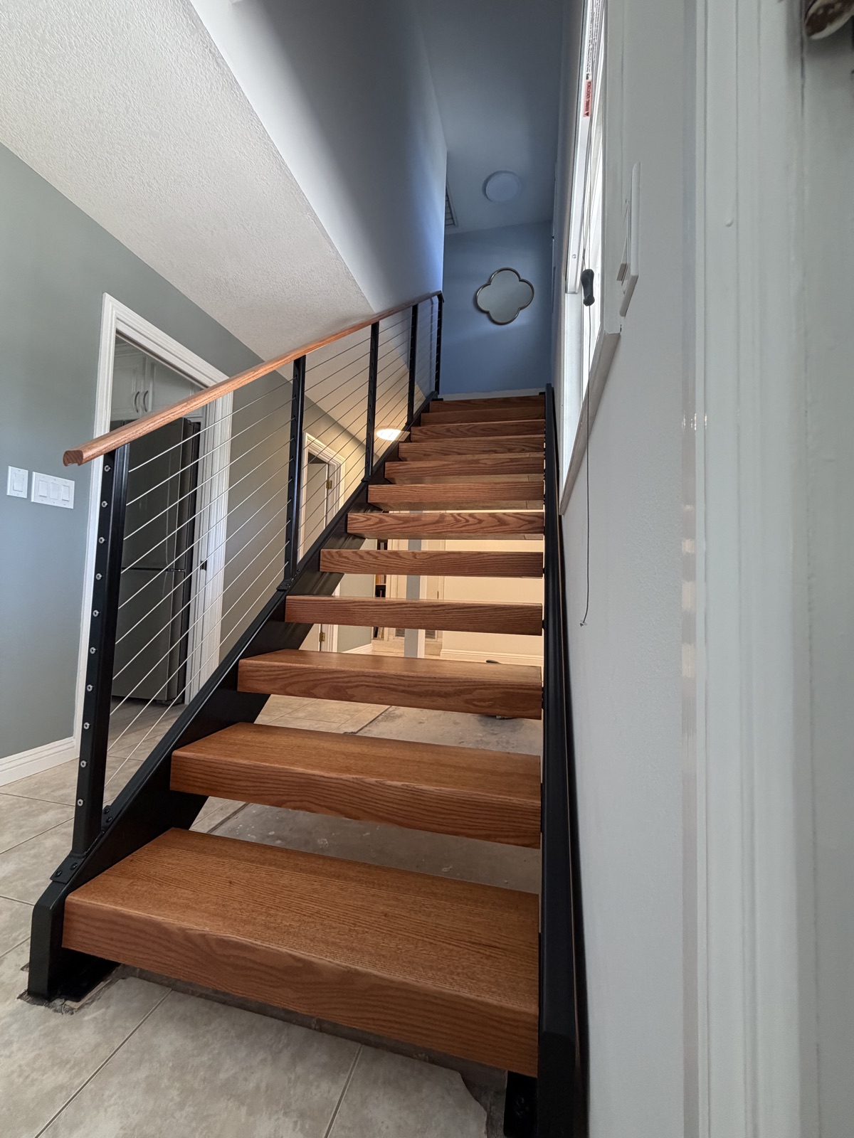 After: floating oak treads with a black steel and cable railing