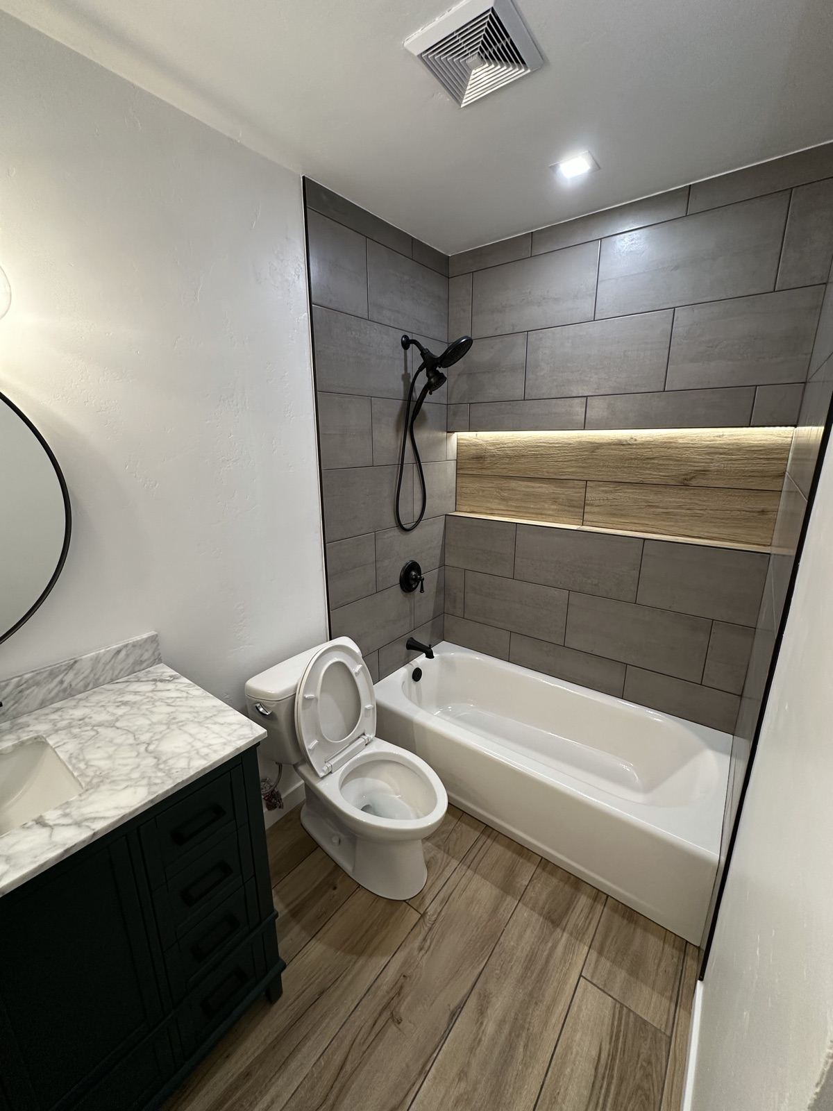 Fully remodeled bathroom with large-format gray tile and wood accent band in Lakeside
