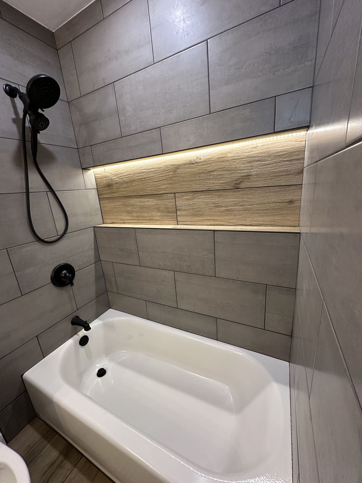 New tub and tile surround with backlit wood accent shelf in Lakeside