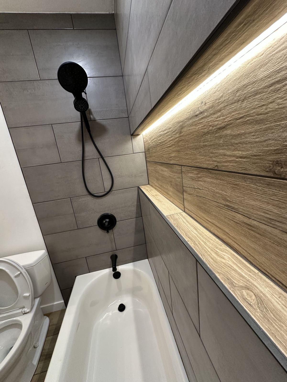 Matte black shower fixtures against tile and wood detailing in the Lakeside remodel