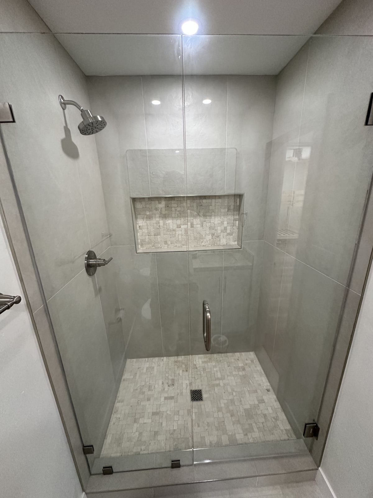 Glass walk-in shower with custom tile niche in the remodeled Oceanside home
