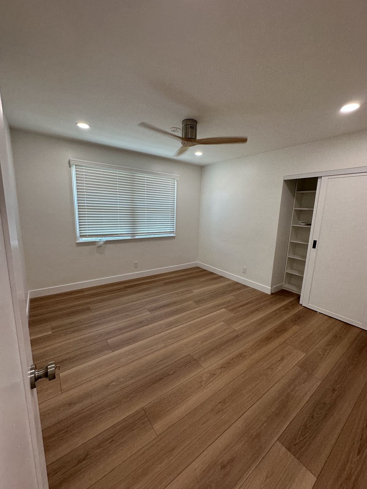 Remodeled bedroom with new wood flooring and ceiling fan in Oceanside